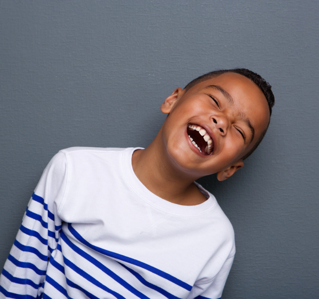 Close up portrait of a happy little boy smiling on gray background.